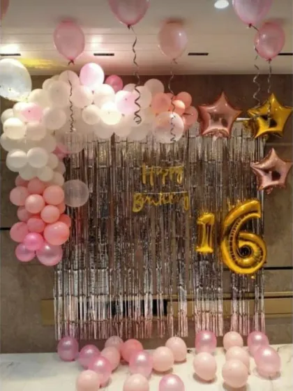 A pretty pink and silver decoration for a 16th birthday. This simple yet elegant setup features a silver fringe backdrop, 'Happy Birthday' foil letters, and a large '16' foil balloon.