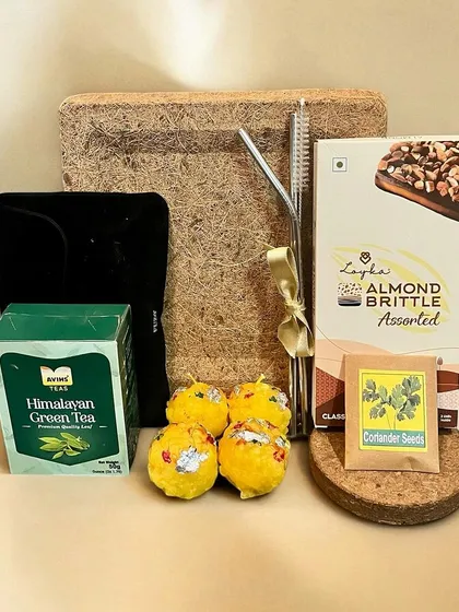 A sustainable and eco-friendly Diwali gift hamper. This set includes green tea, almond brittle, and coriander seeds to plant, all packed in a box made of natural fibers.