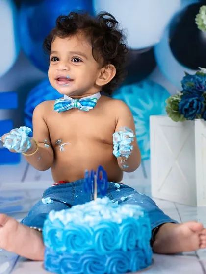 A smile that can light up the whole room. Even covered in cake, his happiness shines through in this first birthday portrait.