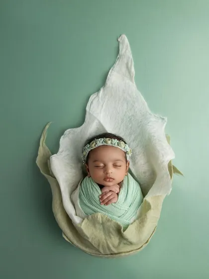 A slightly different pose within the flower prop, this image showcases the baby's delicate hands and the beautiful, handcrafted details of her headband.