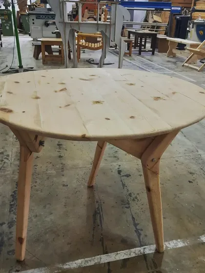 The collapsible table is shown here in its upright, functional position, highlighting the elegant leg design and the beautiful grain of the solid wood top.