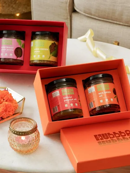 Minimal festive styling for Hubba Hubba Foods' gift boxes, using a diya and marigold flowers to create a subtle Diwali feel.