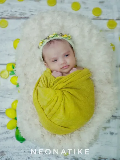A bright and cheerful lemon-themed newborn wrap. The vibrant yellow swaddle and matching headband make for a zesty and adorable portrait.