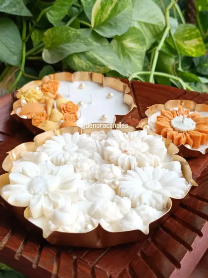 I offer urli candles in a variety of sizes and designs. Here you can see a large all-white floral urli, a smaller sunflower design, and a seashell-themed piece, showcasing the range of styles available.