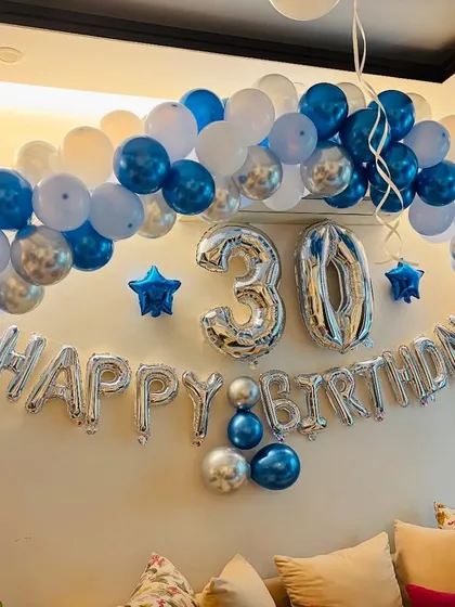 A cool and stylish 30th birthday decoration at home. I used a balloon arch in shades of blue, white, and silver over the sofa.