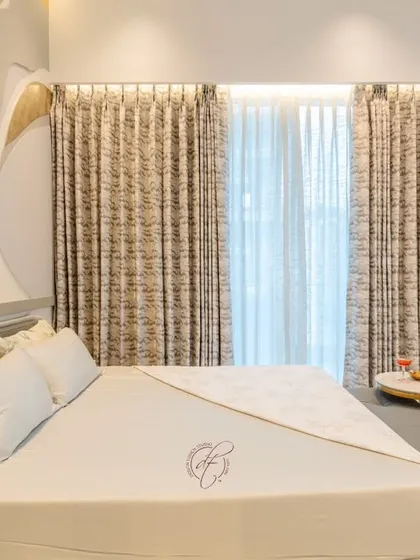 This angle highlights the layered curtains and the soft, natural light they filter into the room. The design creates a bright and airy atmosphere, perfect for relaxation.