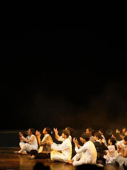 A scene of reverence and unity from our "Inquilab" performance. A large group of dancers is seated before a standing figure, showcasing our skill in choreographing for large ensembles and creating impactful stage formations.
