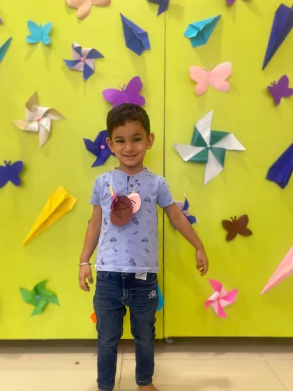 A proud smile in front of our craft wall. This student is happy to stand by the colorful paper crafts, some of which he helped create during our after-school sessions.