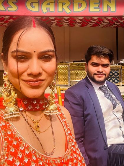 A selfie of a client and her partner at an outdoor wedding function. She is wearing a beautiful red choker and matching oversized earrings from my collection.