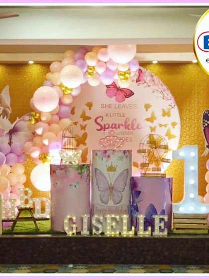 A beautiful butterfly and fairy-themed first birthday. The pink and purple decor features a 'She leaves a little sparkle' backdrop, a 'GISELLE' marquee, and a large light-up number '1'.