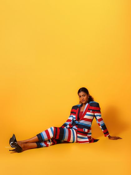 A relaxed, seated pose on the floor against the yellow backdrop. The wide-angle composition creates a sense of space and freedom.