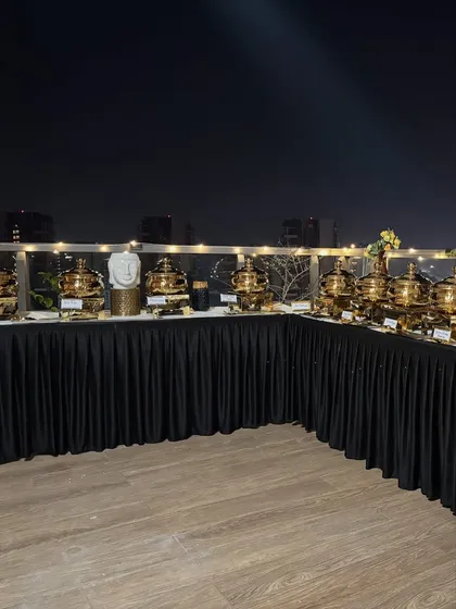 A wide shot of the rooftop buffet line, with decorative Buddha heads and fairy lights creating a serene and stylish atmosphere.