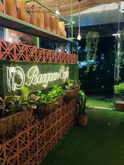 The entrance to our cafe at night, with the neon sign glowing against the terracotta brick wall and lush planters. It’s the first hint of the green world that awaits you inside.