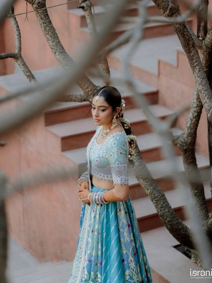 A thoughtful and serene portrait of the bride before her Mehendi ceremony. The natural branches create a beautiful, artistic frame for the shot.