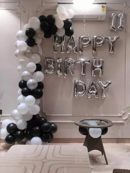 A stylish black, white, and silver balloon arch in a modern living room. This shows how we can create decorations that match the client's home decor.