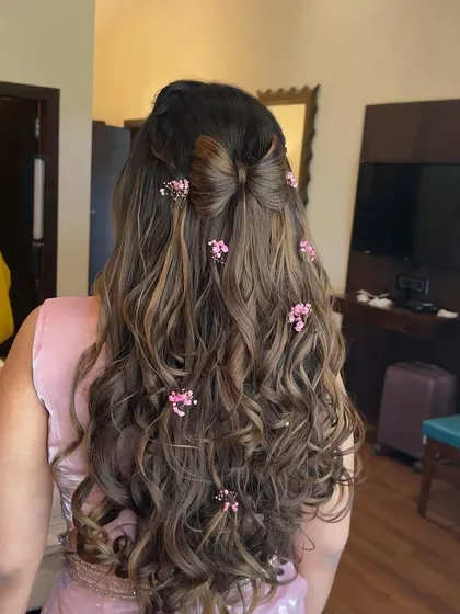 Dreamy Haldi hair for a Barbie moment. This half-up bow hairstyle is decorated with tiny pink flowers, creating a super cute and feminine look for the bride-to-be.