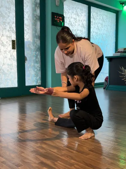 Guiding a student into a squat, I check her balance and alignment. This fundamental movement is a building block for powerful jumps and stable landings in dance.