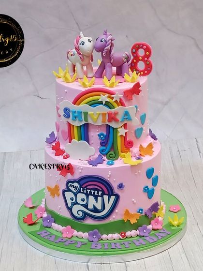 A fun two-tier "My Little Pony" themed cake for an 8th birthday. The pink cake is decorated with fondant ponies, a rainbow, and the official logo for a fan's dream celebration.