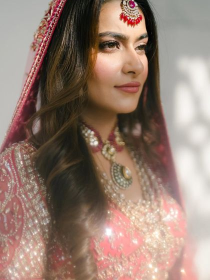 A classic beauty shot. The soft, golden light illuminates the bride's face, highlighting her features and the delicate details of her jewelry.