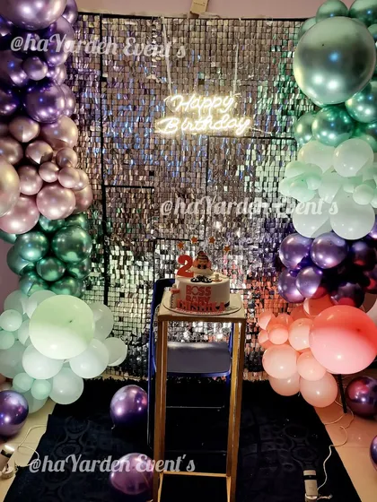 Another angle of the multi-colored metallic balloon and sequin wall setup, showing the cake on a pedestal, ready for the celebration.