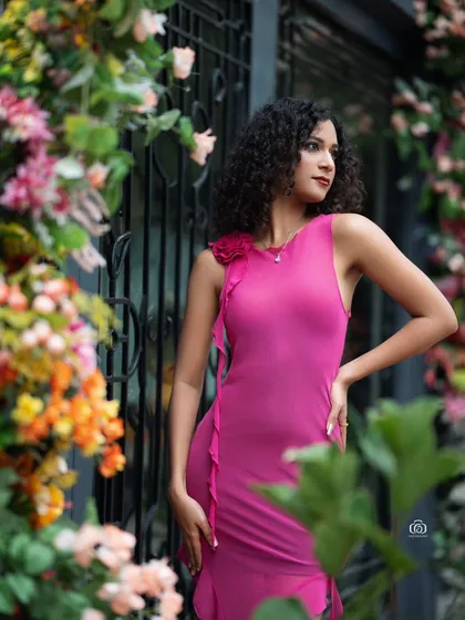 A portrait of the model in a pink dress, looking off to the side. The out-of-focus flowers in the foreground and background create a beautiful sense of depth.