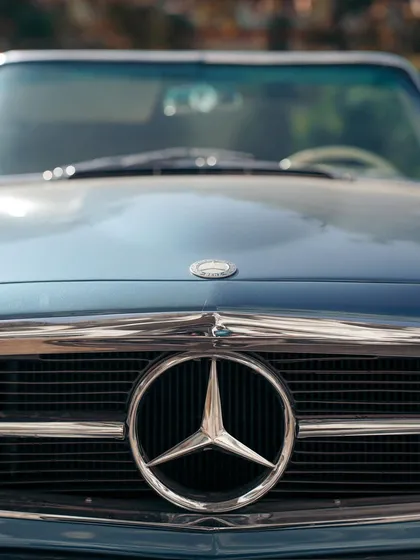 The iconic three-pointed star of a vintage Mercedes-Benz. This close-up on the grille emblem is a tribute to a legacy of automotive excellence.