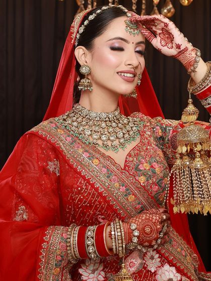 A shy bride with her hand on her forehead, giving a beautiful glimpse of her intricate mehandi design.