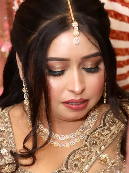 A close-up of the bride's face, showing off the stunning golden glitter eye makeup and flawless base.