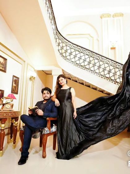 A grand pre-wedding portrait in a luxurious hall, with the couple posed on a majestic staircase, her black trail gown adding to the opulence.
