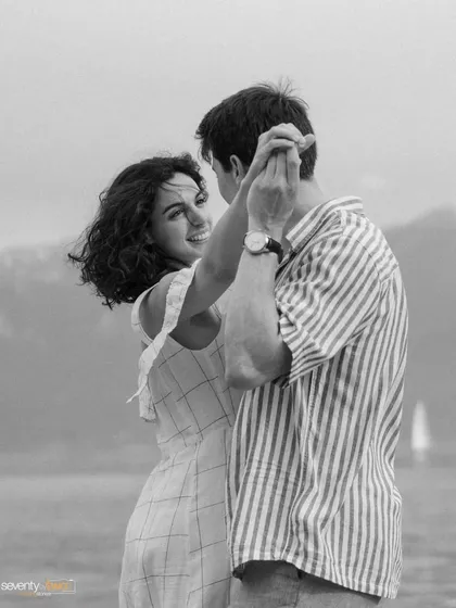 A dance by the lake. This timeless black and white portrait captures a moment of graceful movement and romance, their figures soft against the water.