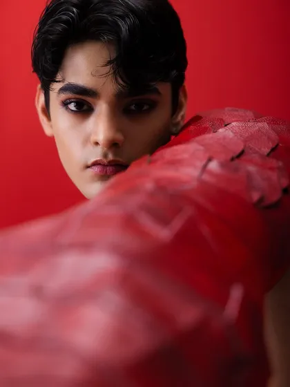 An example of my editorial work with male models. Here, I used a smokey eye to create a dramatic, high-contrast look that complements the avant-garde styling and intense red background of the shoot.