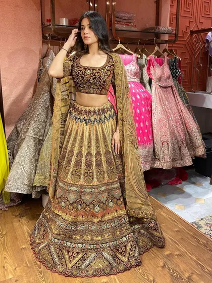 This heavily embroidered lehenga is a true work of art. The combination of mustard and maroon with detailed threadwork makes it a standout piece for any bride.
