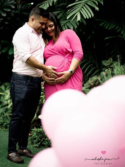 This couple used a vibrant pink dress and heart-shaped balloons for their gender reveal shoot, anticipating a baby girl. Using color and props is a fun way to build excitement and create memorable announcement photos.