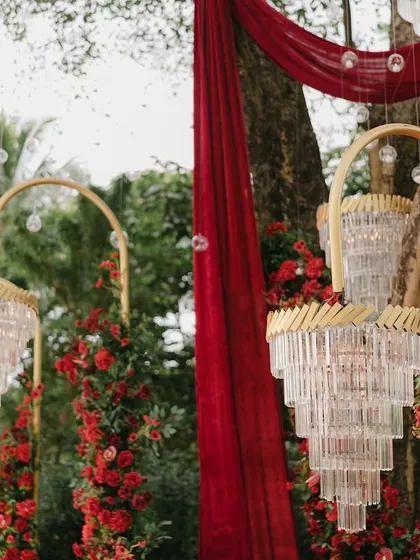 Detail shot of the art-deco style chandeliers and red floral arrangements used in the passionate red-themed engagement decor.