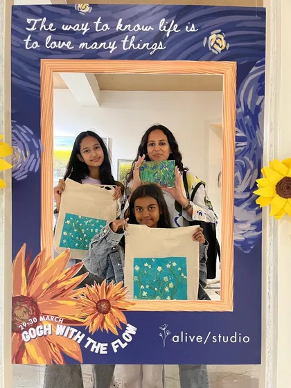 A family poses with their finished artworks, including painted tote bags, during our Van Gogh event.