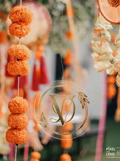 A custom monogram featuring the couple's initials, hanging amidst traditional marigold garlands. This small detail is a great way to personalize the decor and reinforce the celebration of their union.