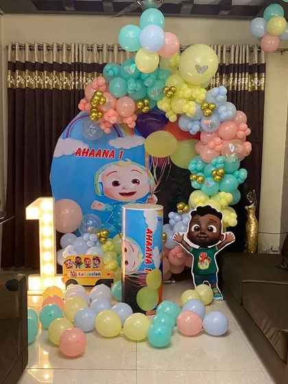 A complete view of the Cocomelon home birthday decoration. The setup fits perfectly in a living room space, combining a backdrop, balloon arch, and marquee number for a full party look.