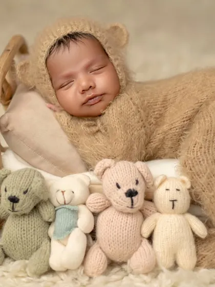 The full lineup of teddy bears watching over this sleeping baby. A fun and adorable setup for a newborn session.