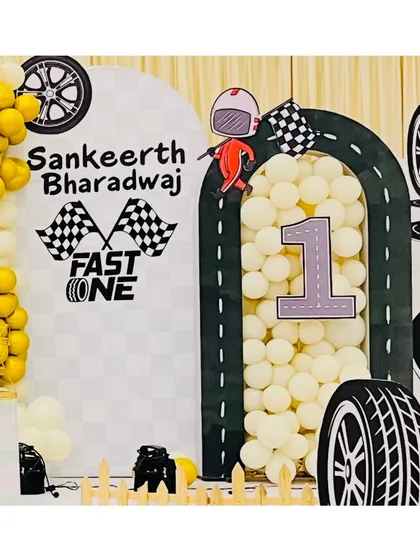 A personalized arch for Sankeerth Bharadwaj's "Fast One" birthday. The decor includes checkered flags, a racer cutout, and the child's name, making the theme feel extra special and customized.