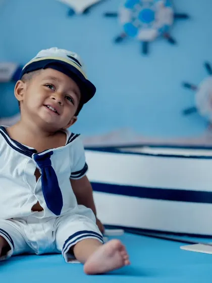 A charming smile from our little sailor. This nautical themed shoot uses a simple blue backdrop and props to create a classic and adorable portrait for toddlers.