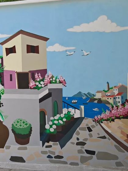 A section of the large European streetscape mural, showing the detailed architecture and seaside view.