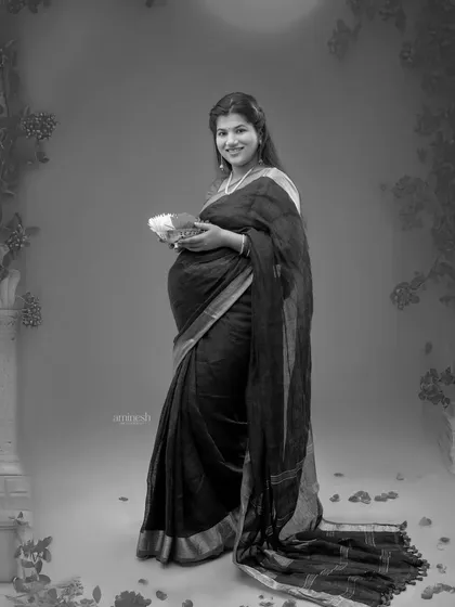 This black and white full-length shot emphasizes the elegant drape of the saree and the traditional setting. It creates a feeling of nostalgia and grace.