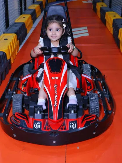 This little girl is all set for a fun ride, safely strapped into her go-kart and ready to navigate the track.