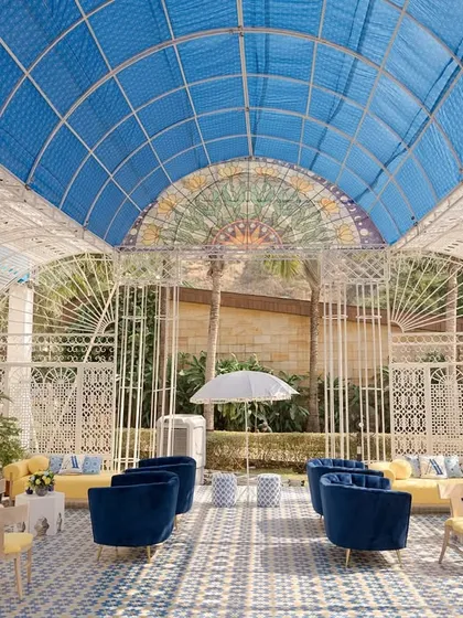 The stunning glasshouse structure we created for Aashvi and Akash's Jodhpur-themed Haldi. The blue and white tiled floor, yellow lounge furniture, and airy structure created a bright and cheerful atmosphere.