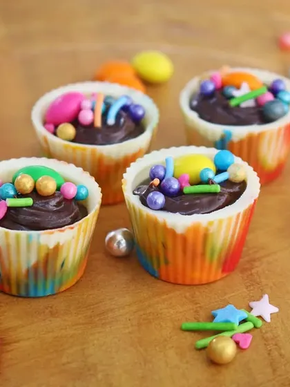 Colorful mini chocolate cups filled with ganache and topped with sprinkles. This close-up shot captures the fun and detail of bite-sized party treats.