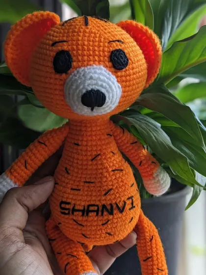 A bright orange tiger doll, also personalized with the name 'Shanvi'.