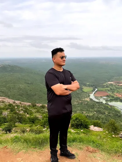 A trekker looking out over the green valley from the Makalidurga peak, a view that makes the climb worthwhile.