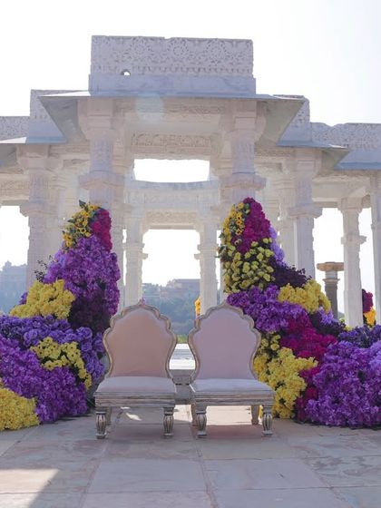 A frontal view of the Haldi seating area, where two chairs for the couple are framed by magnificent, cascading floral installations.
