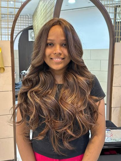 A full view of our hot mocha brown balayage. This technique is perfect for adding brightness and the illusion of volume to long hair, styled here with glamorous waves.