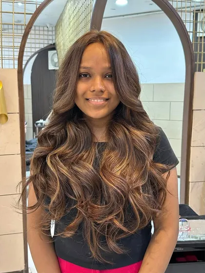 A full view of our hot mocha brown balayage. This technique is perfect for adding brightness and the illusion of volume to long hair, styled here with glamorous waves.